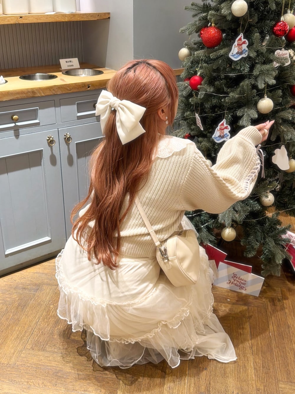 ホワイト系のニット/セーター、ホワイト系のスカート、ホワイト系のショルダーバッグを着用したレディースの冬コーディネートの2枚目の写真