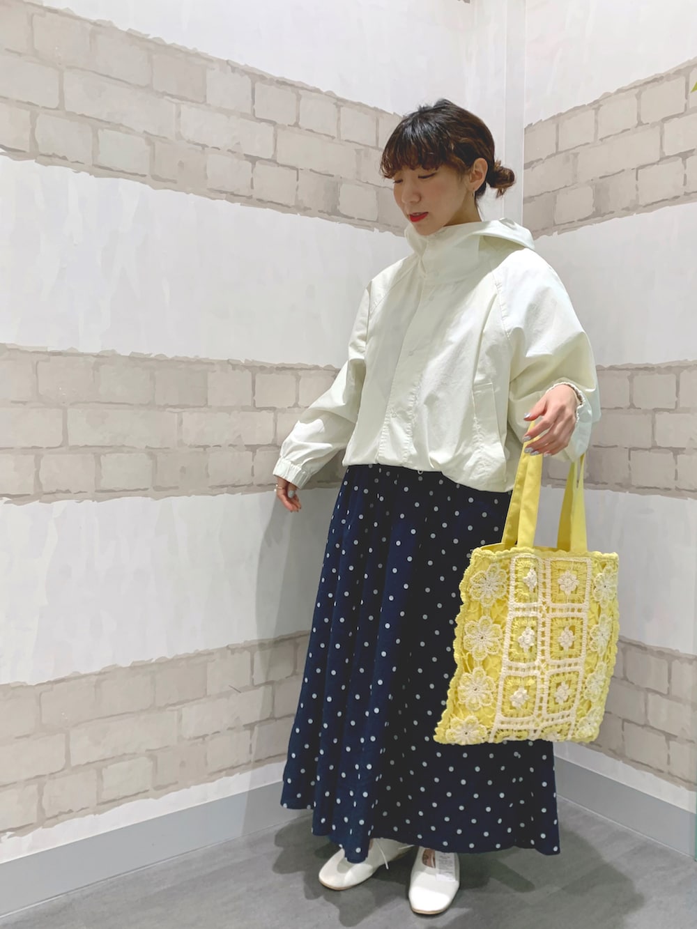 イエロー系のトートバッグ、イエロー系のTシャツ/カットソー、ホワイト系のマウンテンパーカーを着用したレディースの春コーディネートの2枚目の写真