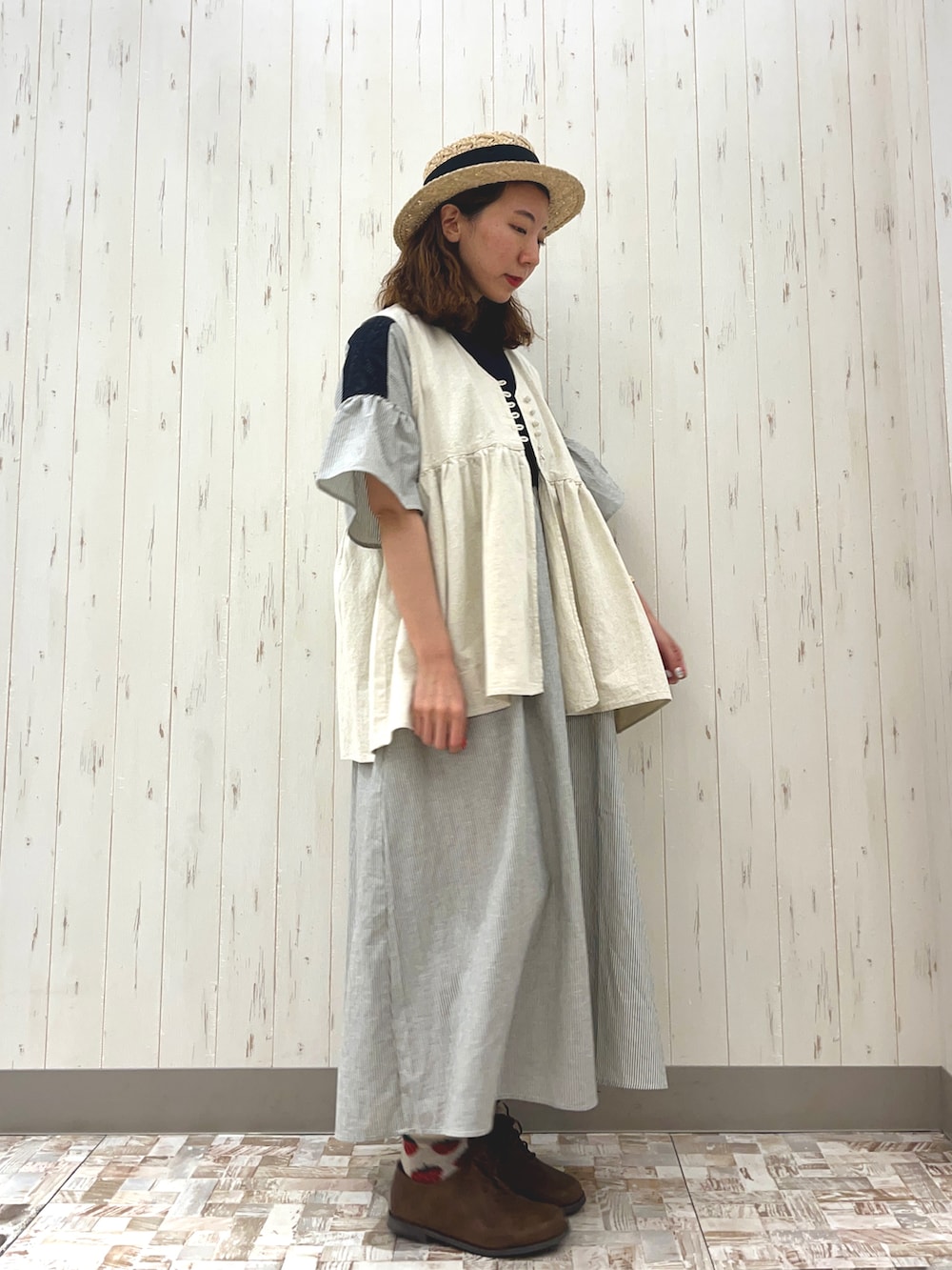 ホワイト系のベスト、ベージュ系のドレスシューズ、ブラック系のワンピースを着用したレディースの春コーディネートの2枚目の写真