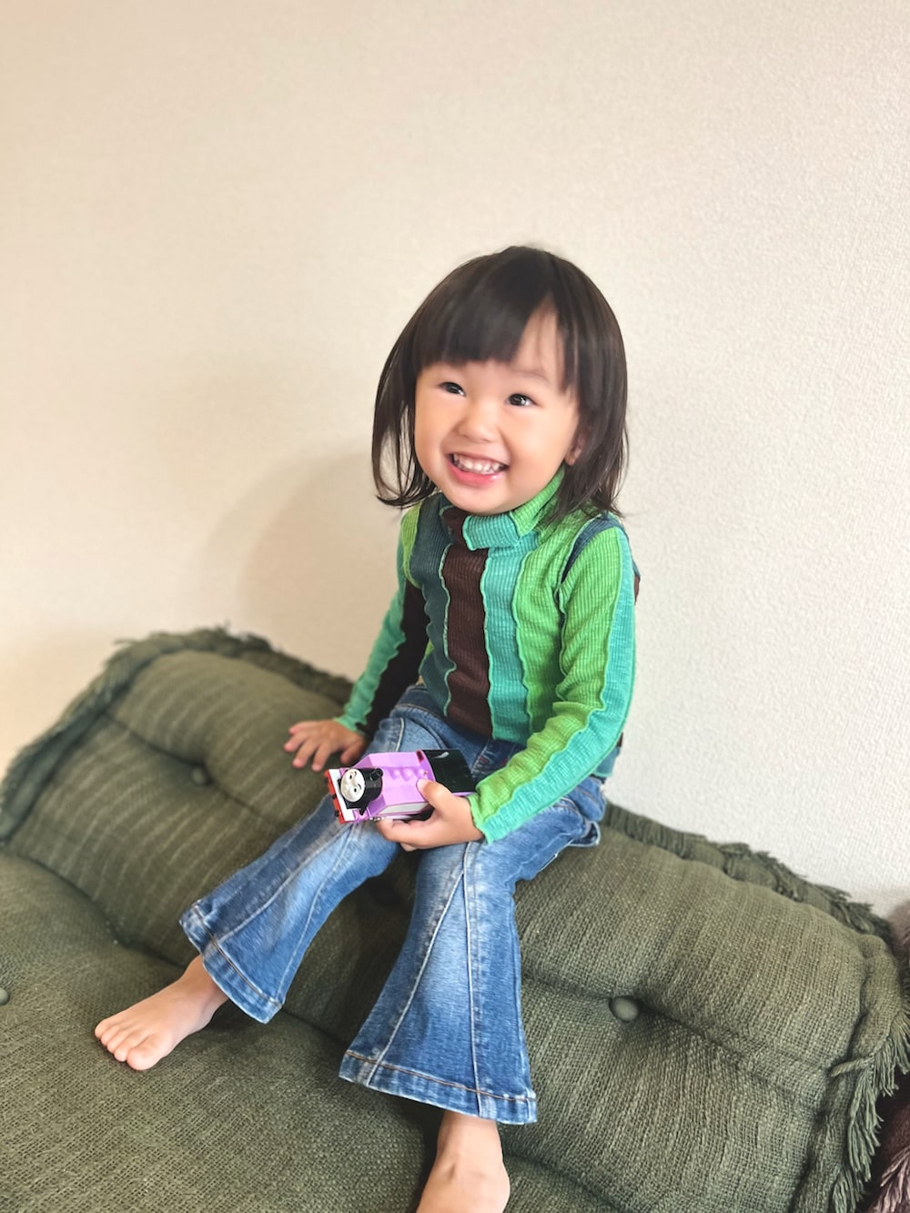 ブルー系のデニムパンツ、グリーン系のトップスを着用したキッズの秋コーディネートの2枚目の写真