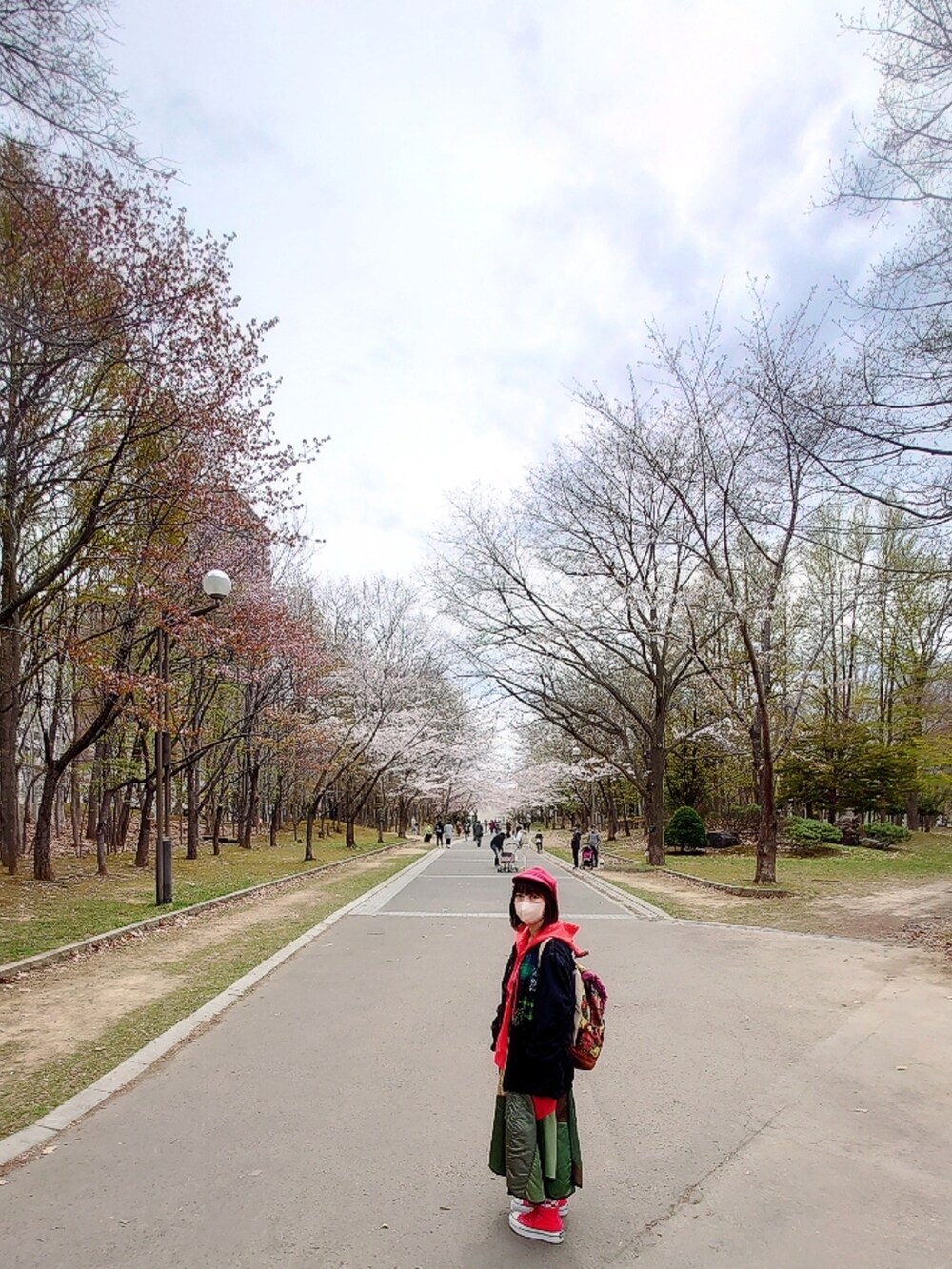 ブルー系のブルゾン、グリーン系のスカート、レッド系のスニーカーを着用したレディースの春コーディネートの3枚目の写真