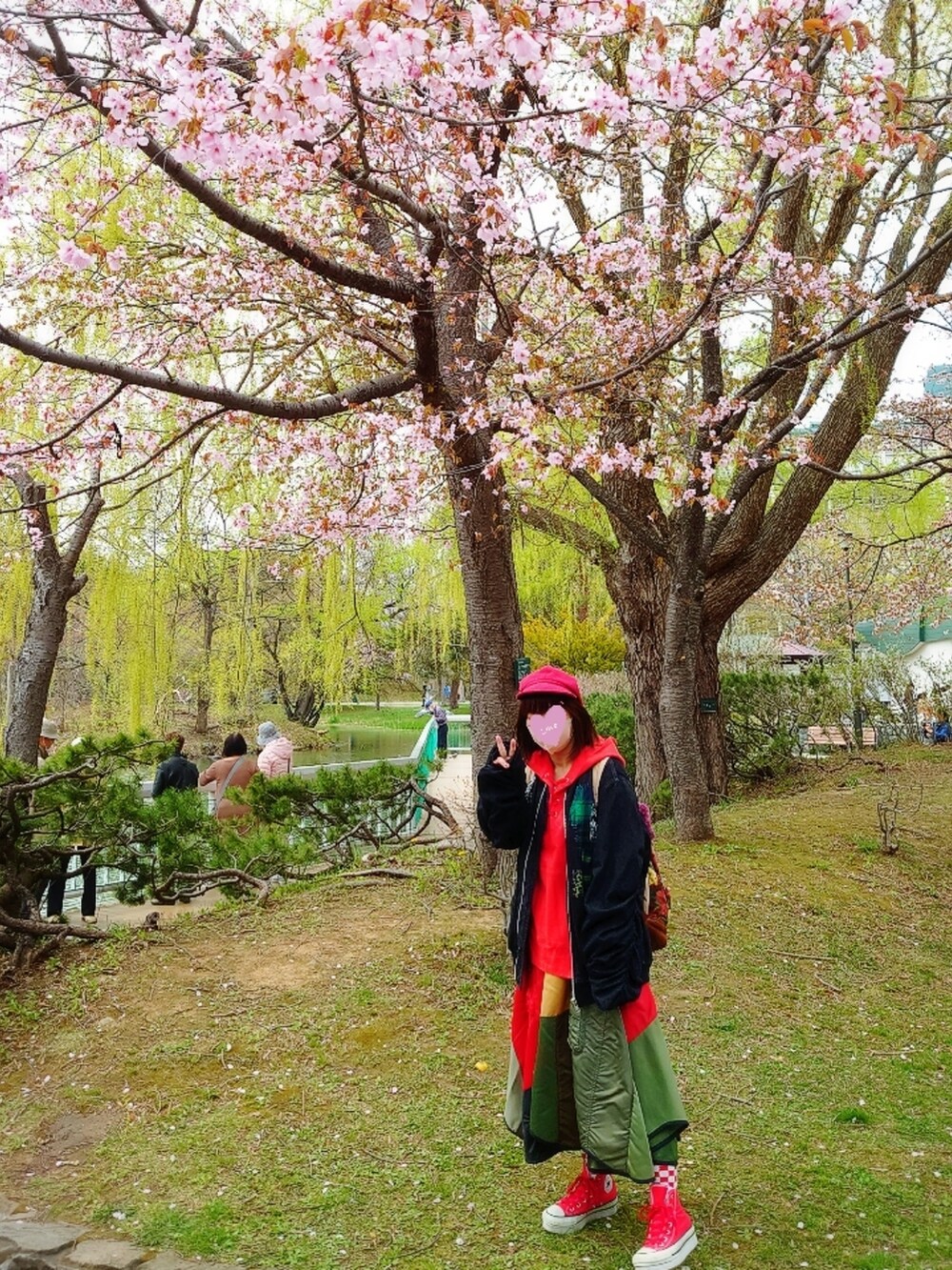 ブルー系のブルゾン、グリーン系のスカート、レッド系のスニーカーを着用したレディースの春コーディネートの2枚目の写真