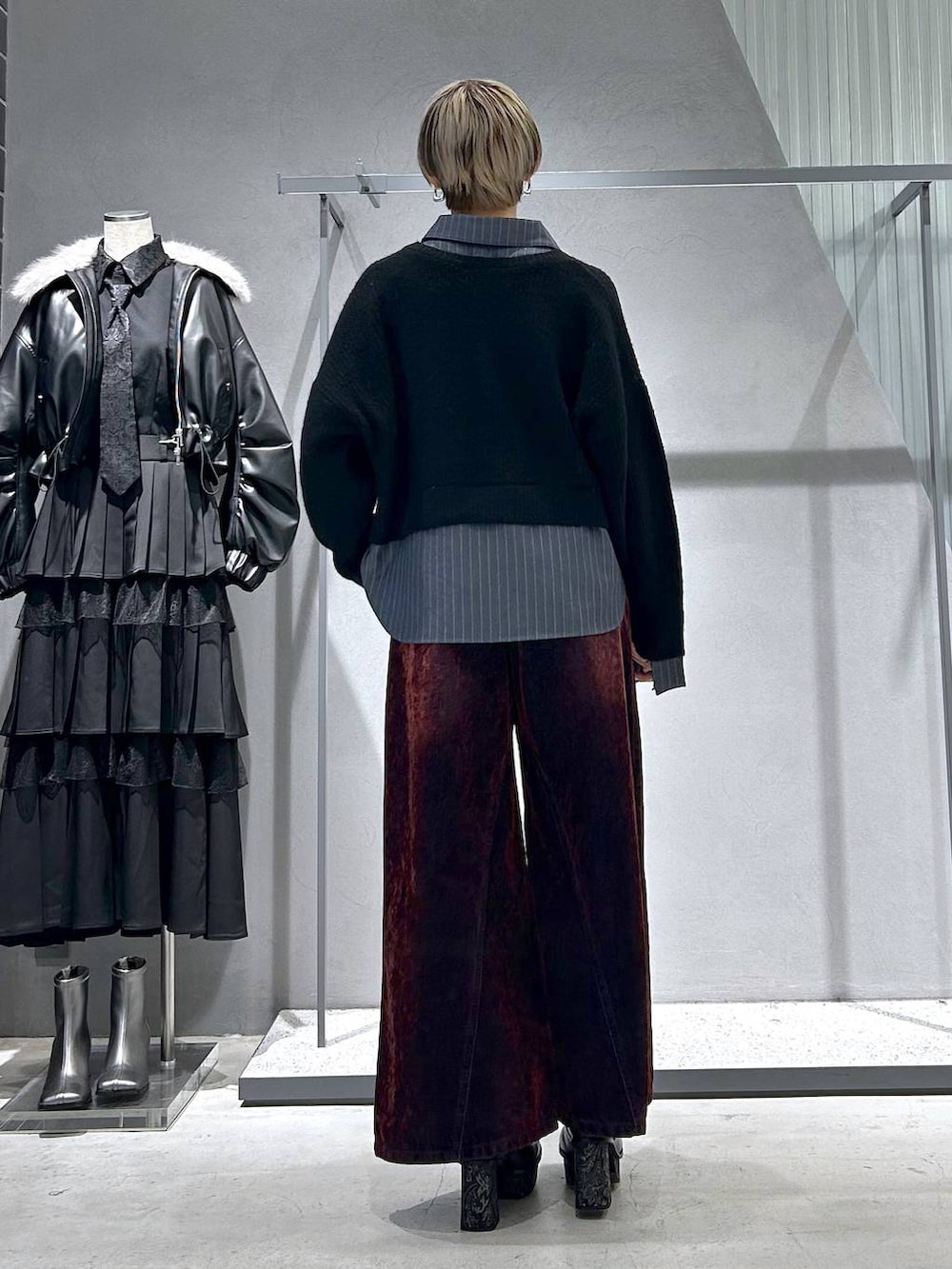 グレー系のブーツ、ブラック系のニット/セーター、レッド系のデニムパンツを着用したレディースの冬コーディネートの6枚目の写真