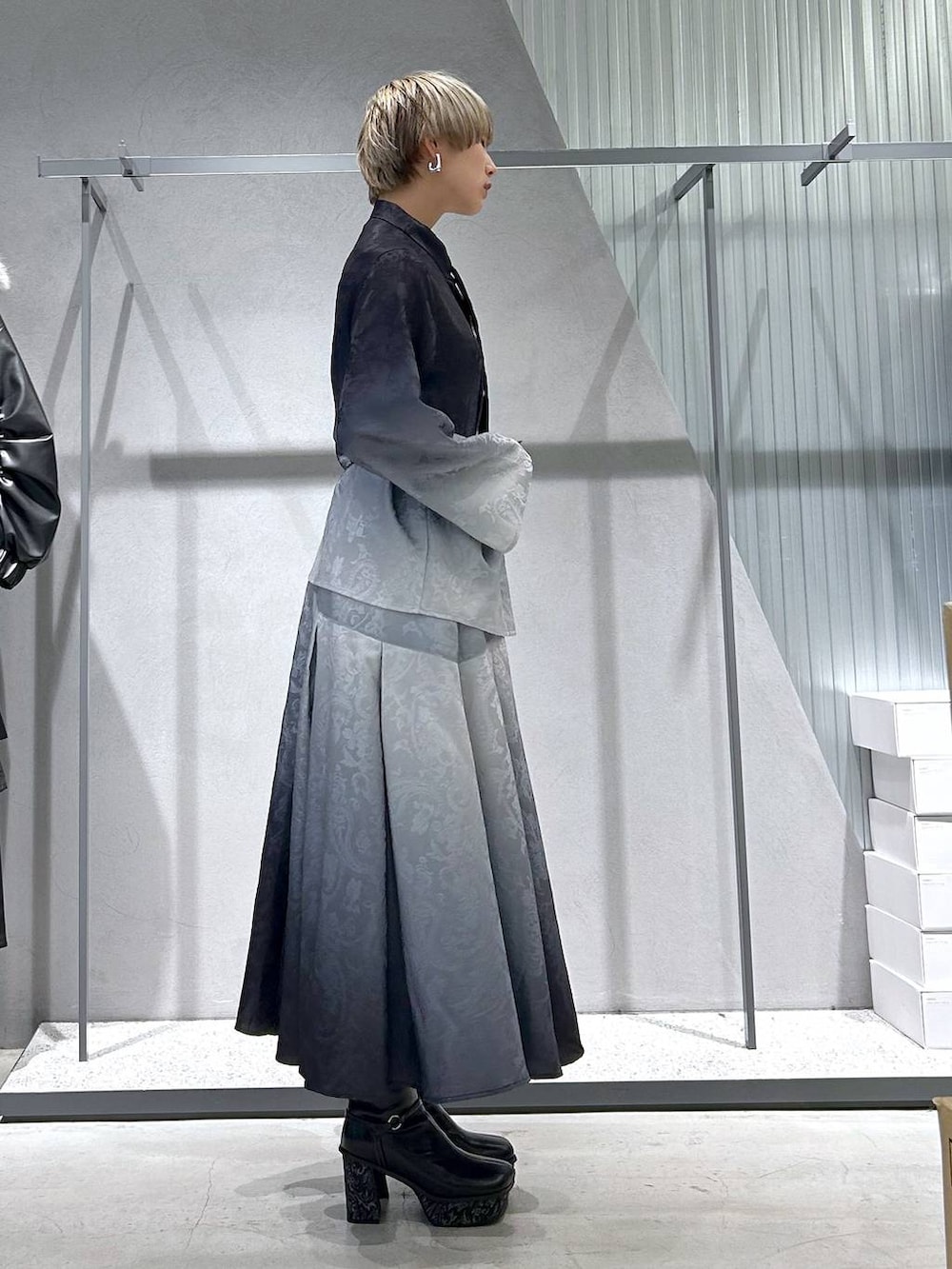 ブラック系のチェスターコート、グレー系のブーツ、ブラック系のシャツ/ブラウスを着用したレディースの冬コーディネートの7枚目の写真