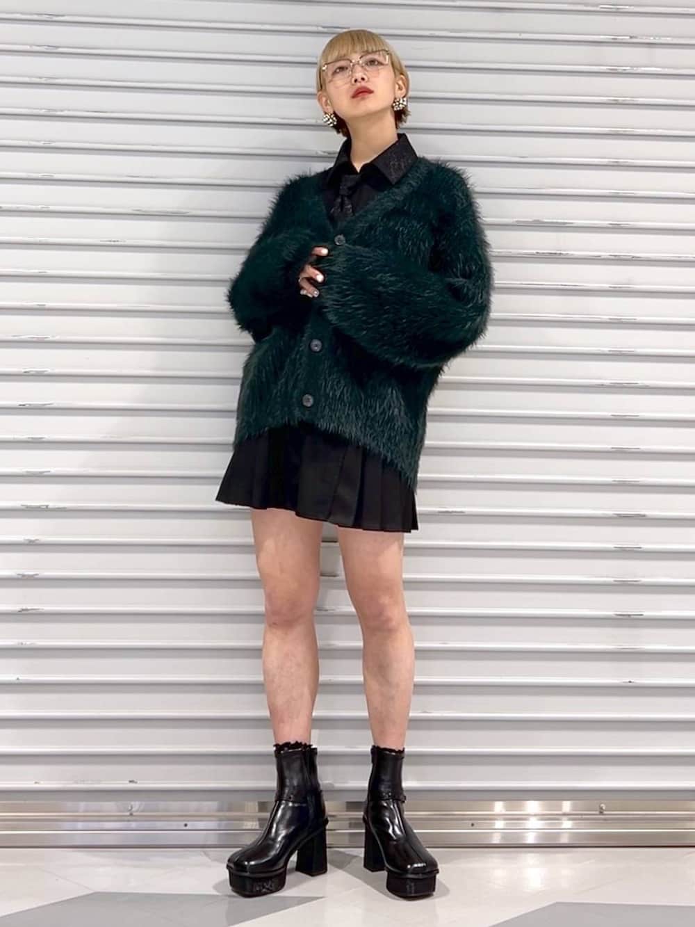 ブラック系のシャツ/ブラウス、グリーン系のカーディガン/ボレロ、ブラック系のブーツを着用したレディースの秋コーディネートの2枚目の写真