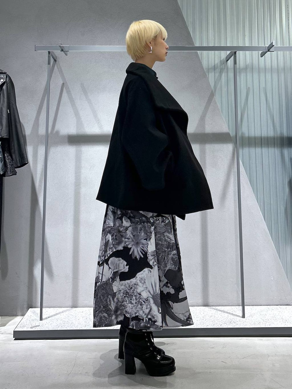 ブラック系のチェスターコート、ブラック系のブーツ、ホワイト系のスカートを着用したレディースの秋コーディネートの5枚目の写真