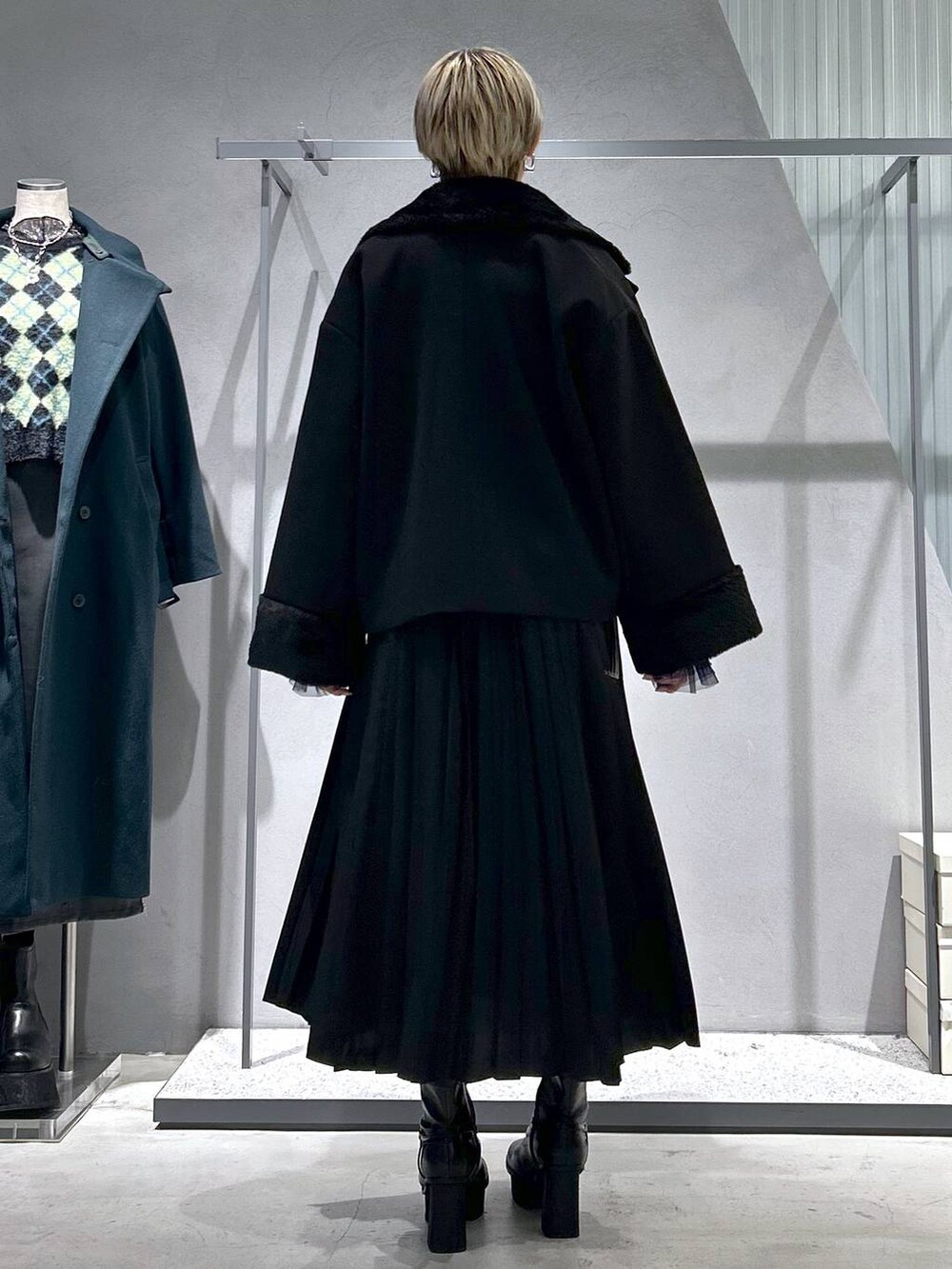 ブラック系のチェスターコート、パープル系のTシャツ/カットソー、グレー系のブーツを着用したレディースの冬コーディネートの4枚目の写真