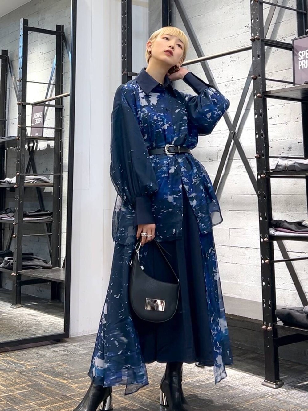 ブラック系のハンドバッグ、ブラック系のブーツ、ブルー系のスカートを着用したレディースの秋コーディネートの2枚目の写真