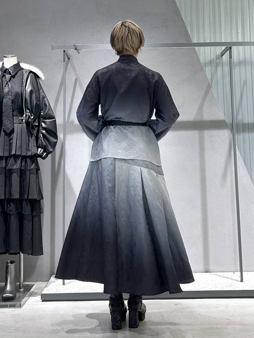 ブラック系のチェスターコート、グレー系のブーツ、ブラック系のシャツ/ブラウスを着用したレディースの冬コーディネートの8枚目の写真