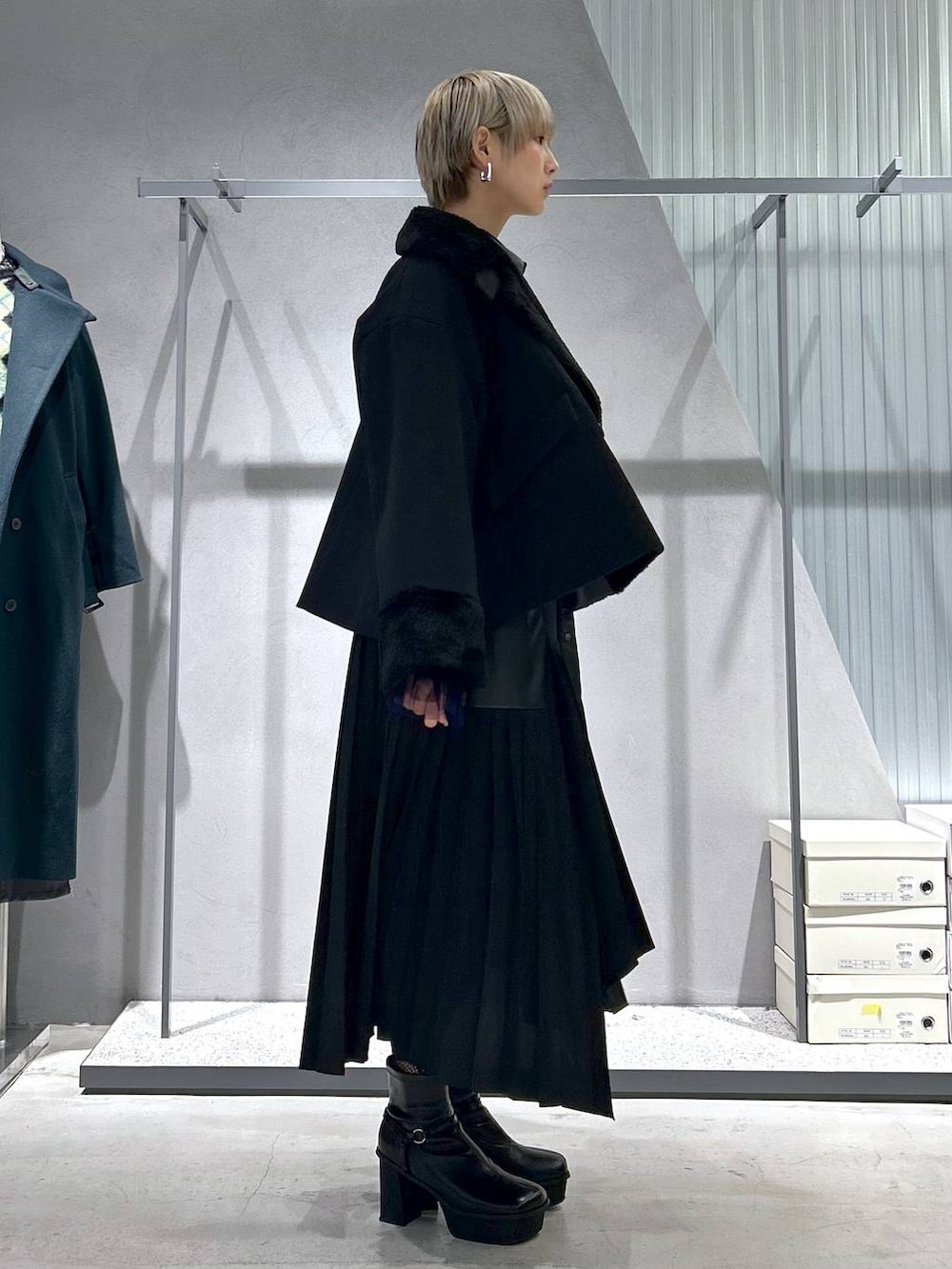 ブラック系のチェスターコート、パープル系のTシャツ/カットソー、グレー系のブーツを着用したレディースの冬コーディネートの3枚目の写真