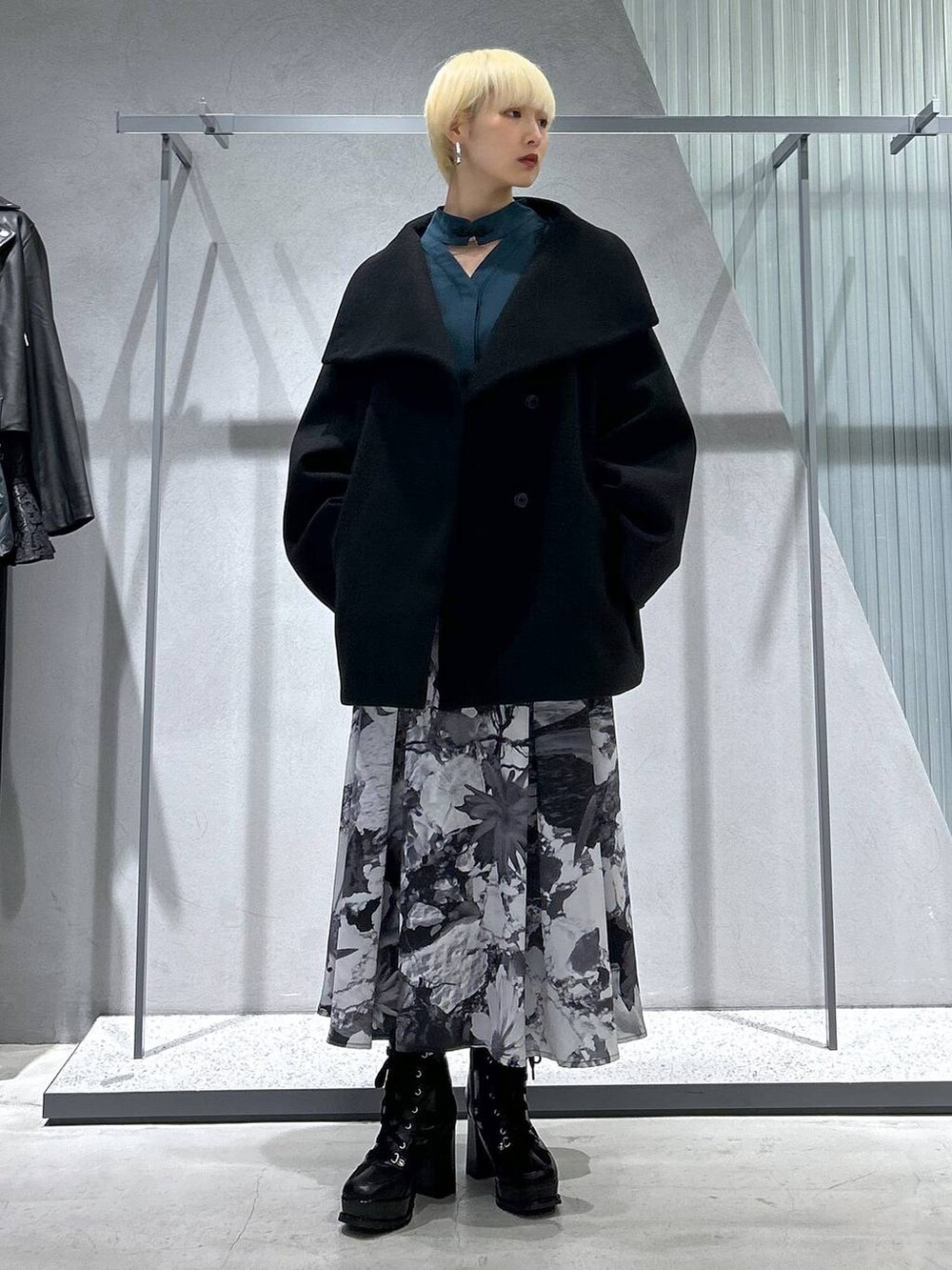 ブラック系のチェスターコート、ブラック系のブーツ、ホワイト系のスカートを着用したレディースの秋コーディネートの4枚目の写真