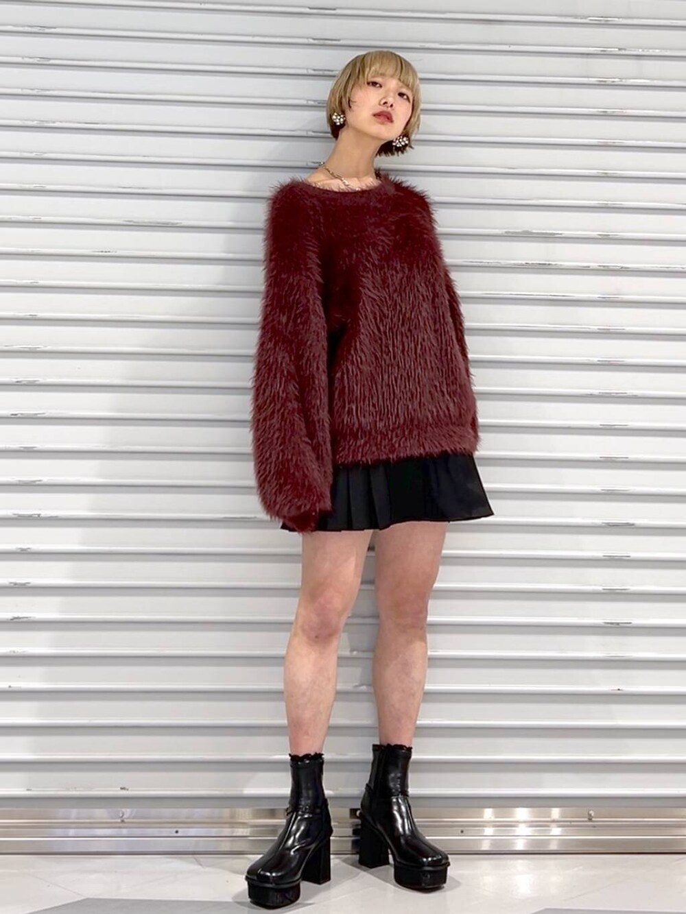 レッド系のニット/セーター、ブラック系のその他パンツ、ブラック系のブーツを着用したレディースの秋コーディネートの4枚目の写真