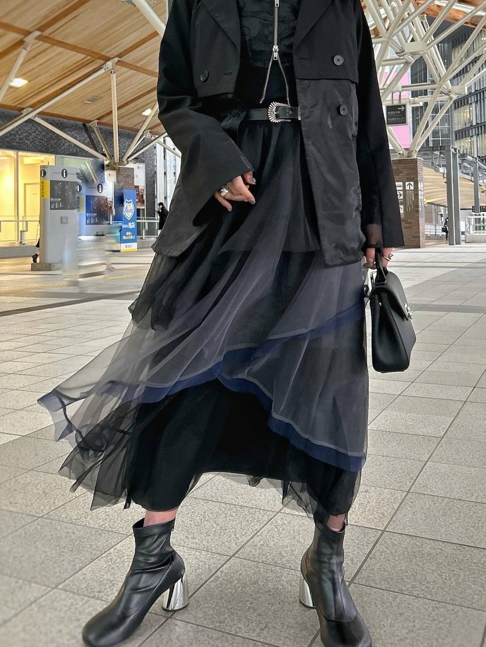 ブラック系のテーラードジャケット、グレー系のスカート、ブラック系のブーツを着用したレディースの春コーディネートの2枚目の写真