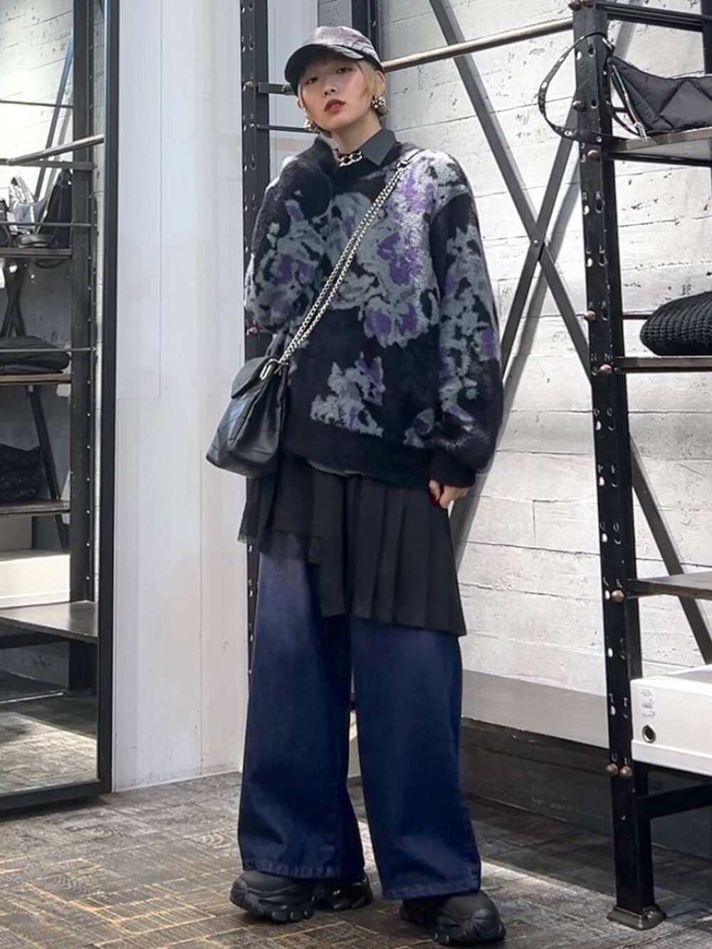 パープル系のデニムパンツ、ブラック系のニット/セーター、ブラック系のブーツを着用したレディースの冬コーディネートの5枚目の写真