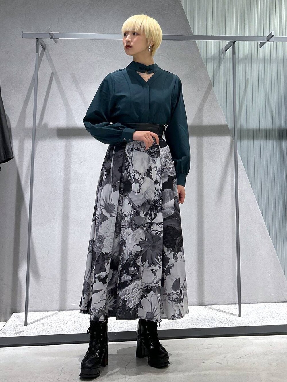 ブラック系のチェスターコート、ブラック系のブーツ、ホワイト系のスカートを着用したレディースの秋コーディネートの2枚目の写真