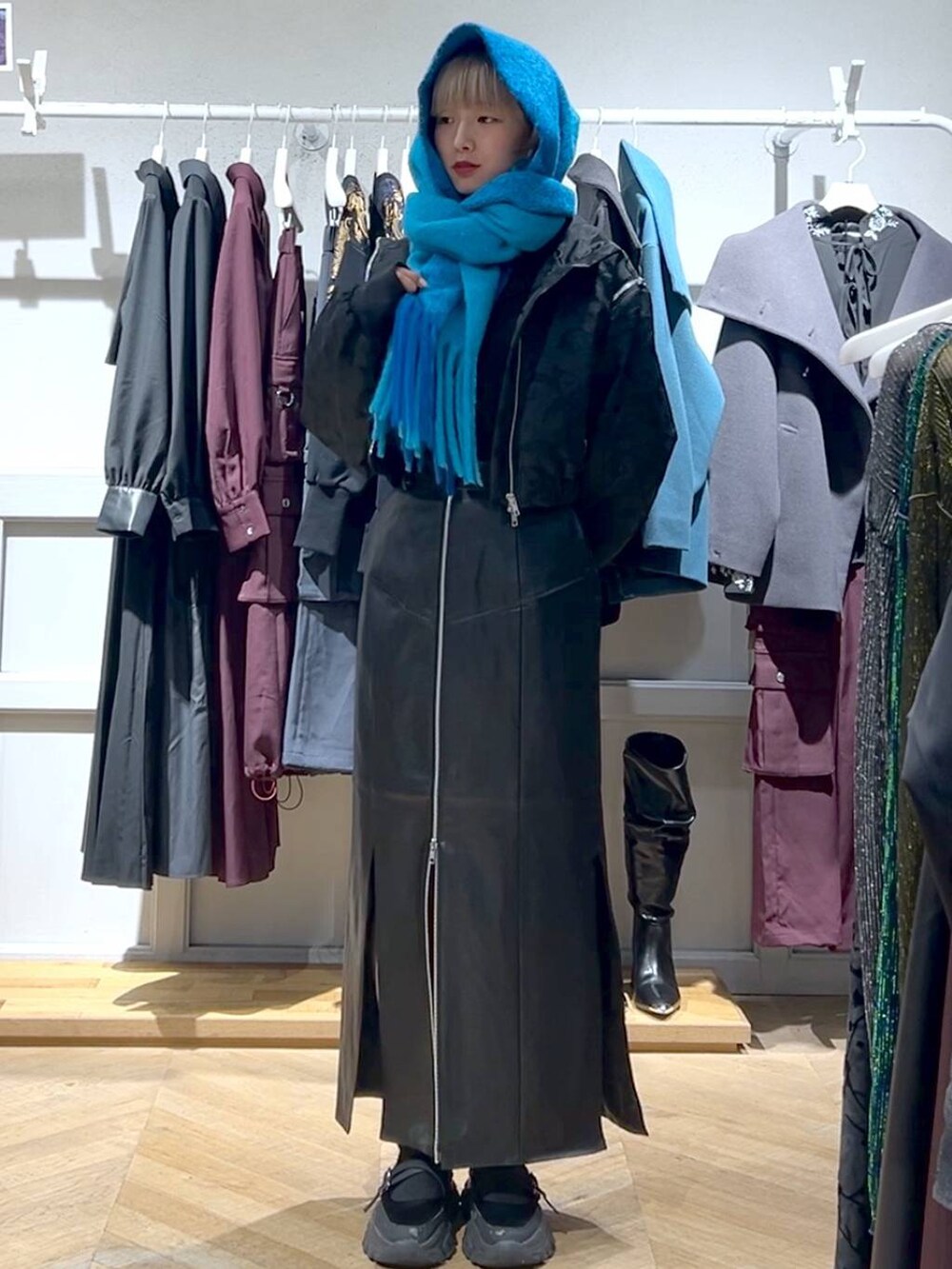 ブラック系のブルゾン、ブラック系のスカート、ブルー系のマフラーを着用したレディースの秋コーディネートの3枚目の写真