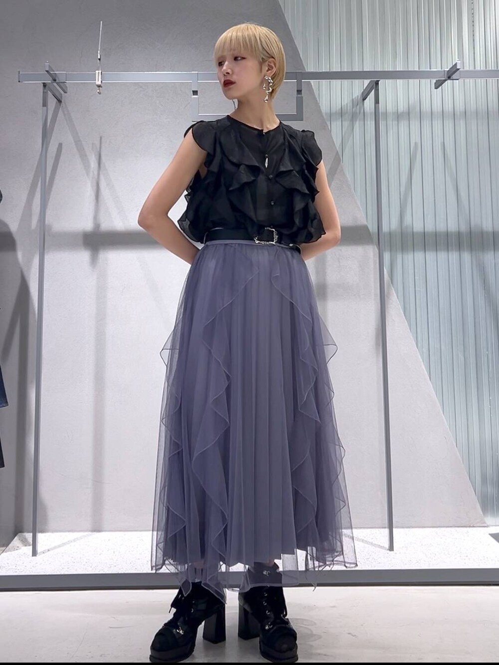 パープル系のスカート、ブラック系のブーツ、ブラック系のシャツ/ブラウスを着用したレディースの春コーディネートの3枚目の写真