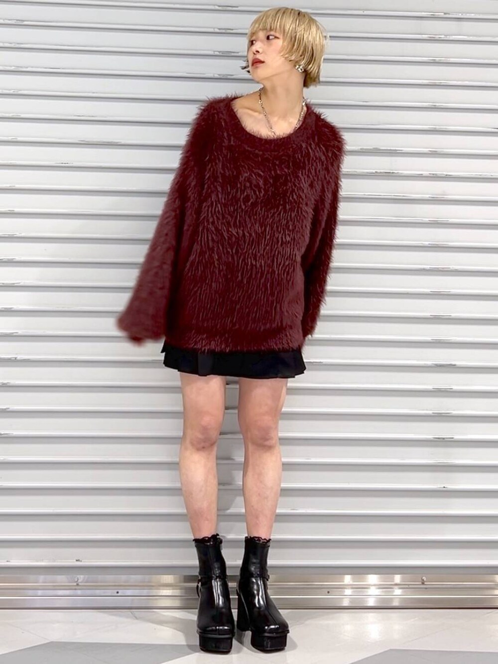 レッド系のニット/セーター、ブラック系のその他パンツ、ブラック系のブーツを着用したレディースの秋コーディネートの2枚目の写真
