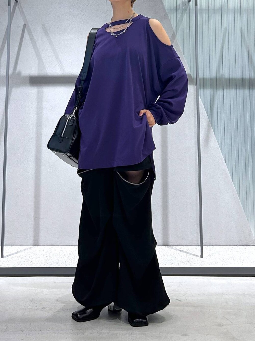 ブラック系のカーゴパンツ、ブラック系のボストンバッグ、パープル系のTシャツ/カットソーを着用したレディースの夏コーディネートの3枚目の写真