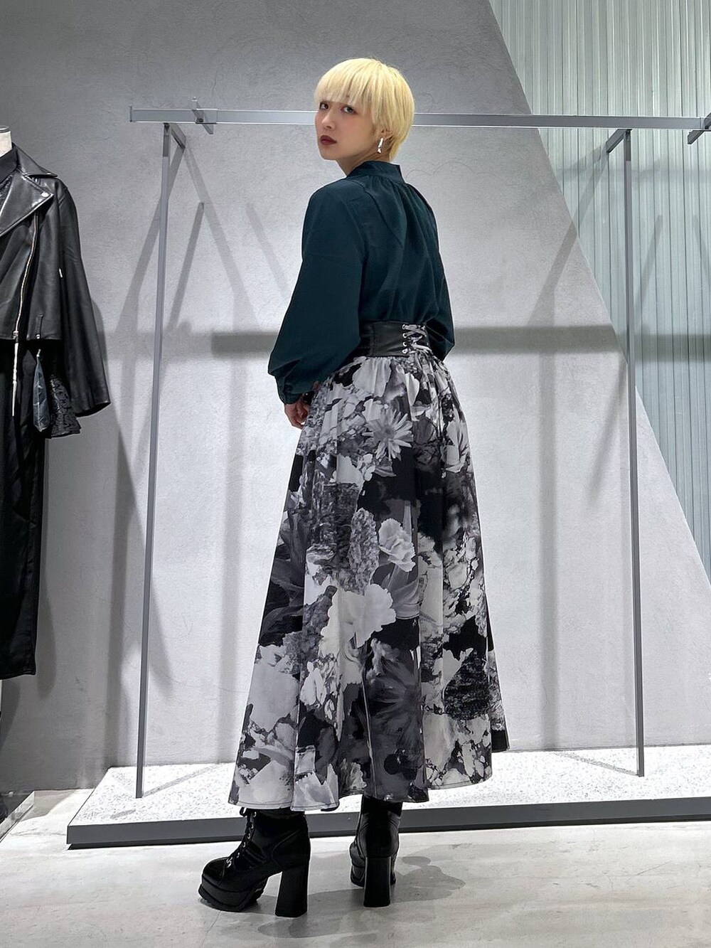 ブラック系のチェスターコート、ブラック系のブーツ、ホワイト系のスカートを着用したレディースの秋コーディネートの3枚目の写真