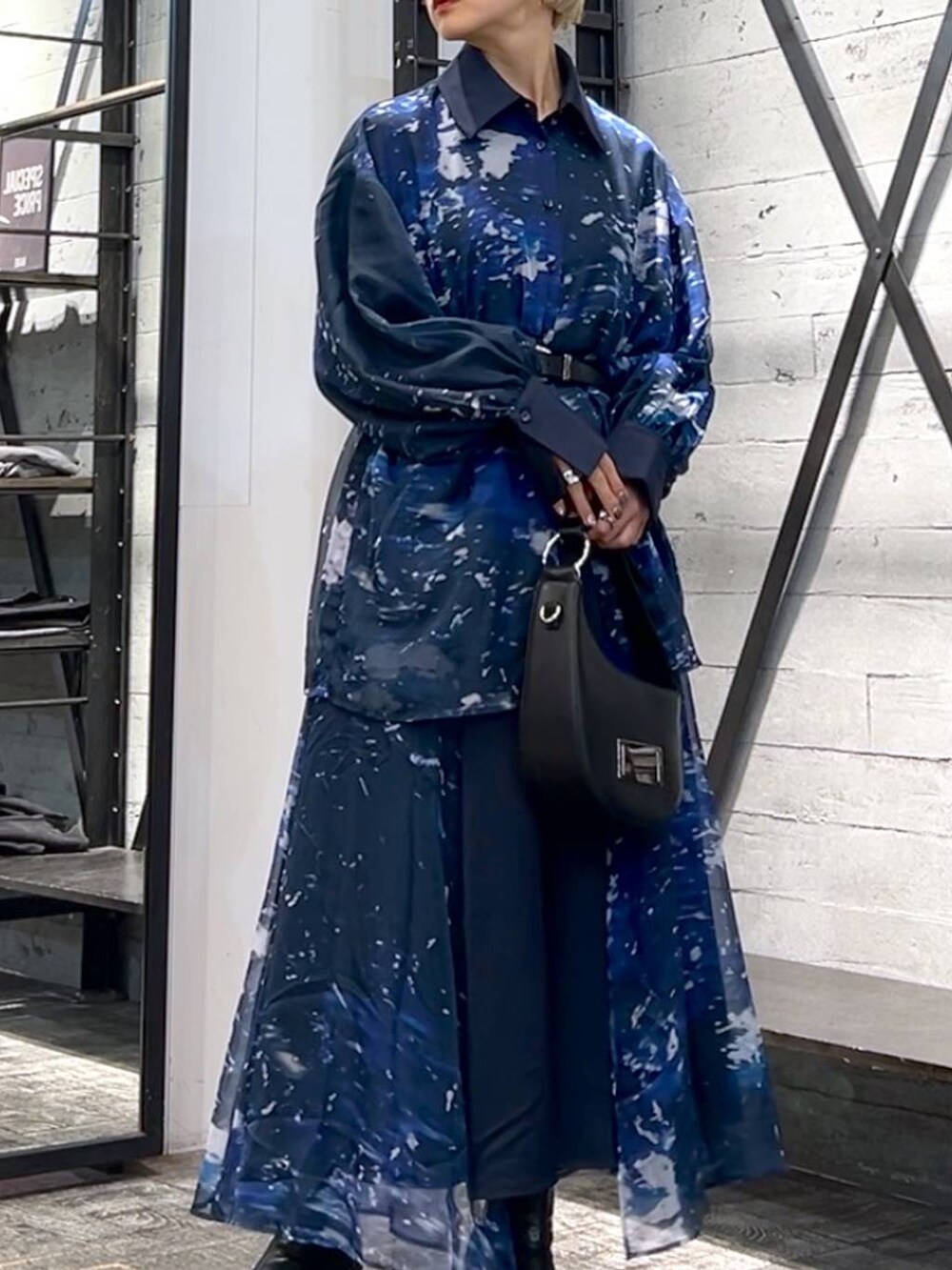 ブラック系のハンドバッグ、ブラック系のブーツ、ブルー系のスカートを着用したレディースの秋コーディネートの5枚目の写真