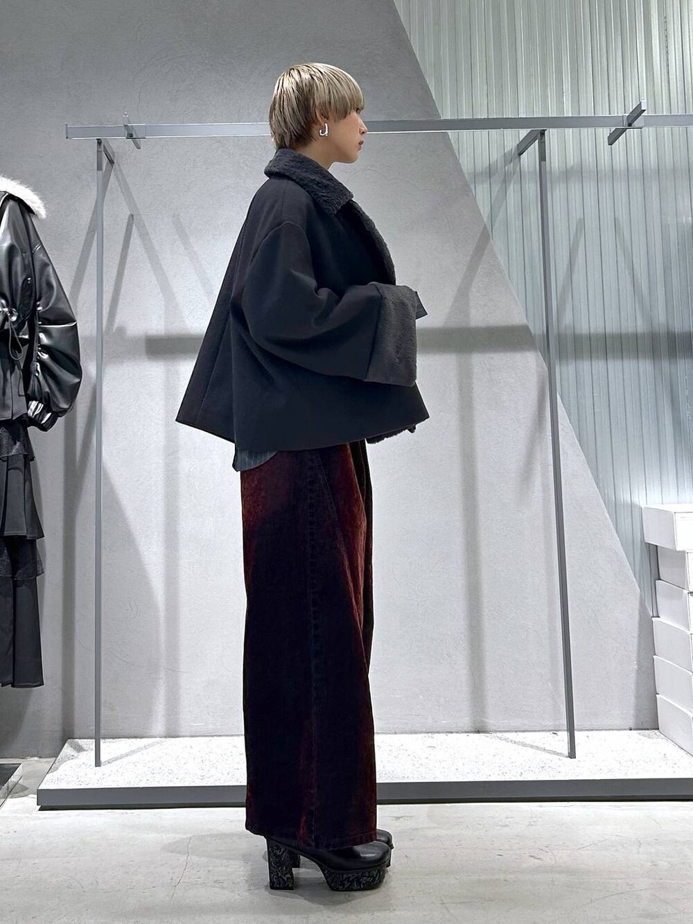 グレー系のチェスターコート、グレー系のブーツ、ブラック系のニット/セーターを着用したレディースの冬コーディネートの3枚目の写真