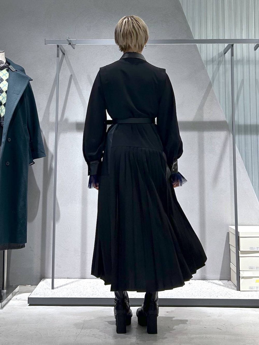 ブラック系のチェスターコート、パープル系のTシャツ/カットソー、グレー系のブーツを着用したレディースの冬コーディネートの6枚目の写真