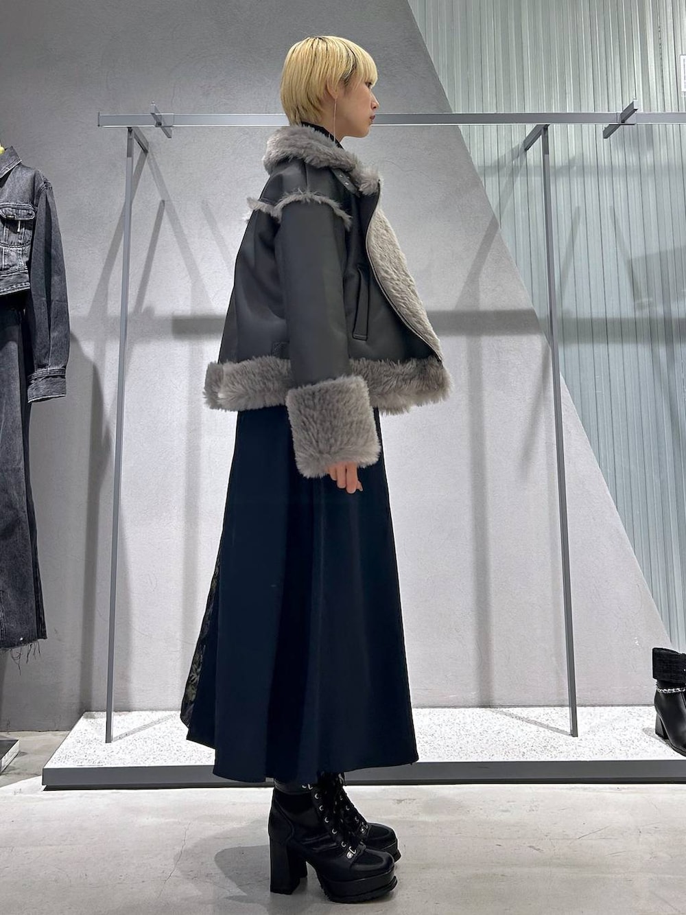 グレー系のムートンコート、ブラック系のブーツ、ブラック系のシャツ/ブラウスを着用したレディースの秋コーディネートの3枚目の写真