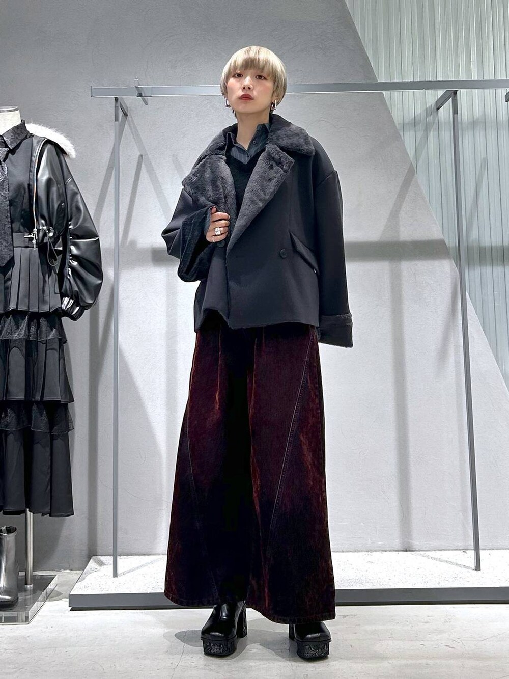 グレー系のチェスターコート、グレー系のブーツ、ブラック系のニット/セーターを着用したレディースの冬コーディネートの5枚目の写真