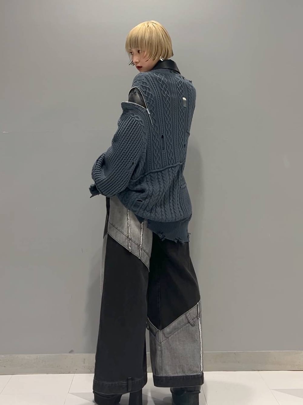 ブラック系のデニムパンツ、ブルー系のカーディガン/ボレロ、ブラック系のブーツを着用したレディースの秋コーディネートの2枚目の写真