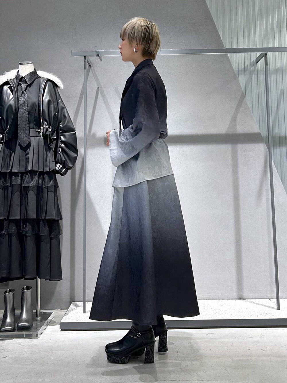 ブラック系のチェスターコート、グレー系のブーツ、ブラック系のシャツ/ブラウスを着用したレディースの冬コーディネートの9枚目の写真