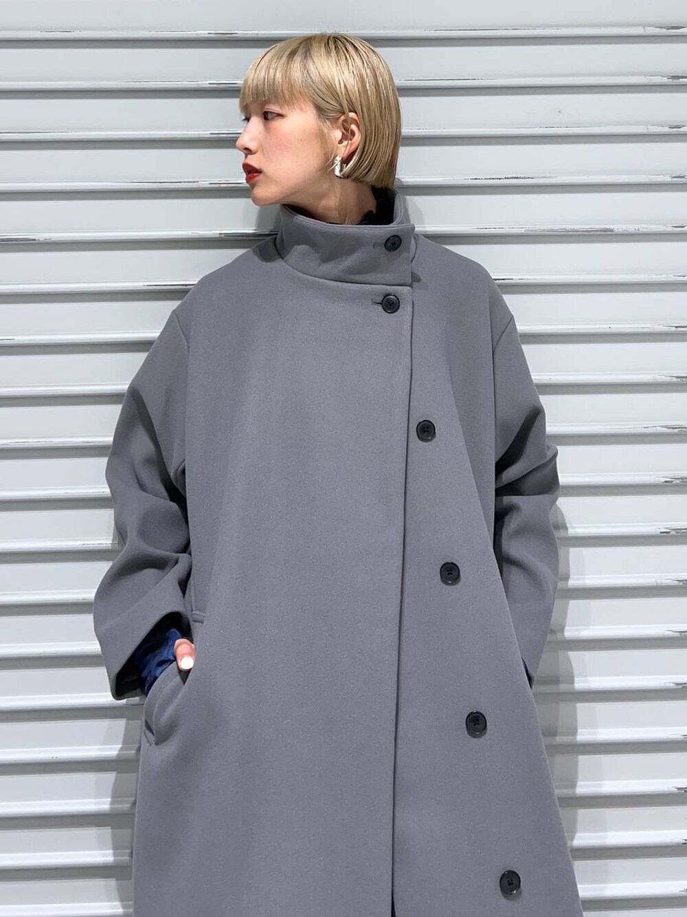 グレー系のチェスターコート、ブラック系のブーツ、ブルー系のスカートを着用したレディースの秋コーディネートの4枚目の写真