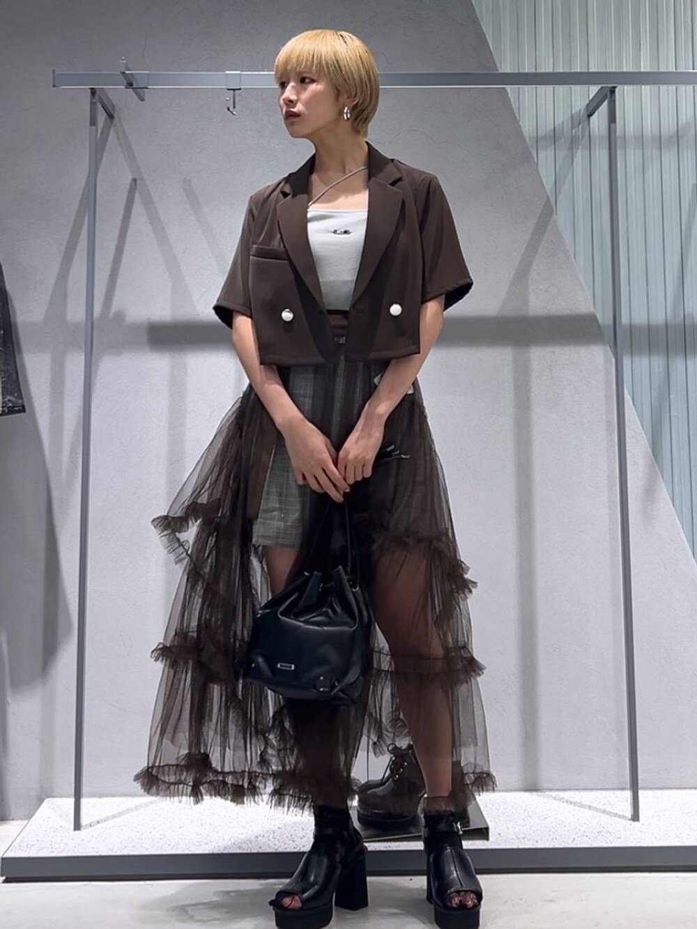 グレー系のサンダル、ブラウン系のテーラードジャケット、ブラウン系のスカートを着用したレディースの夏コーディネートの2枚目の写真