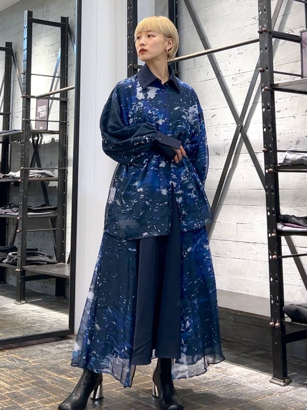 ブラック系のハンドバッグ、ブラック系のブーツ、ブルー系のスカートを着用したレディースの秋コーディネートの4枚目の写真