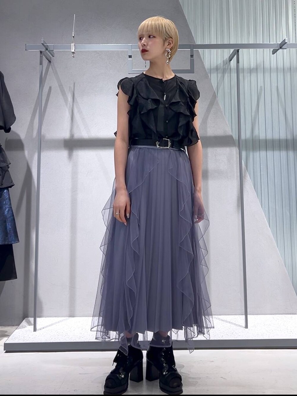 パープル系のスカート、ブラック系のブーツ、ブラック系のシャツ/ブラウスを着用したレディースの春コーディネートの4枚目の写真