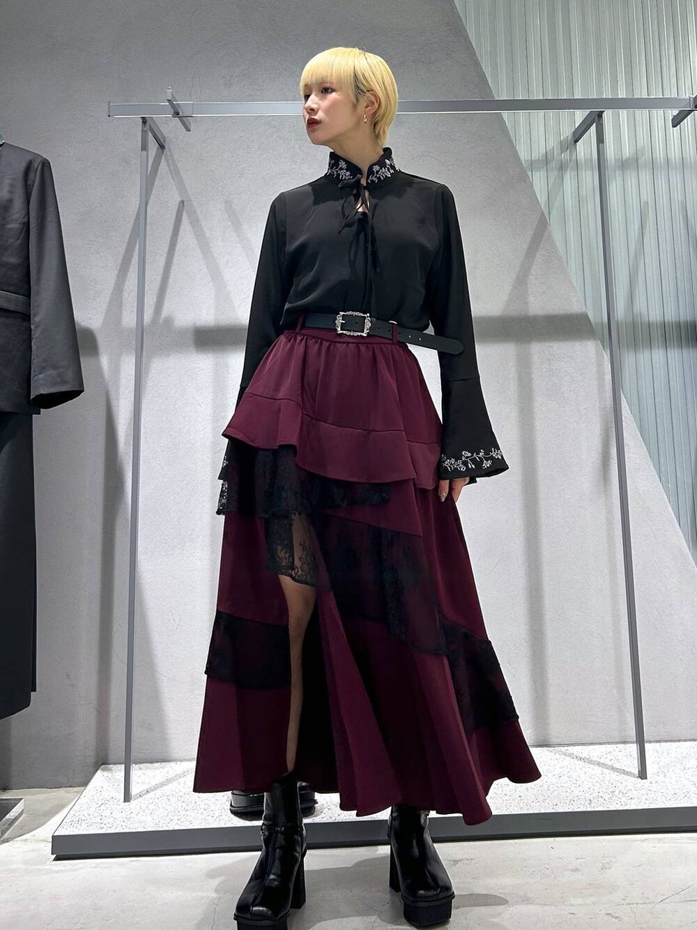 グレー系のブーツ、ブラック系のシャツ/ブラウス、ブラック系のトレンチコートを着用したレディースの秋コーディネートの2枚目の写真