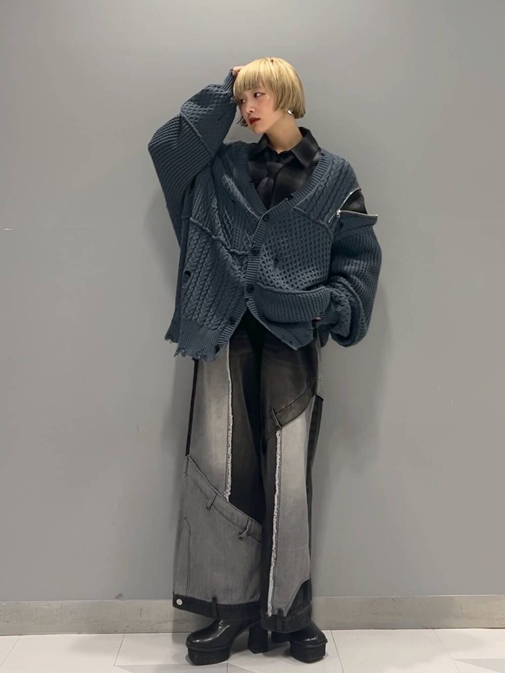 ブラック系のデニムパンツ、ブルー系のカーディガン/ボレロ、ブラック系のブーツを着用したレディースの秋コーディネートの6枚目の写真