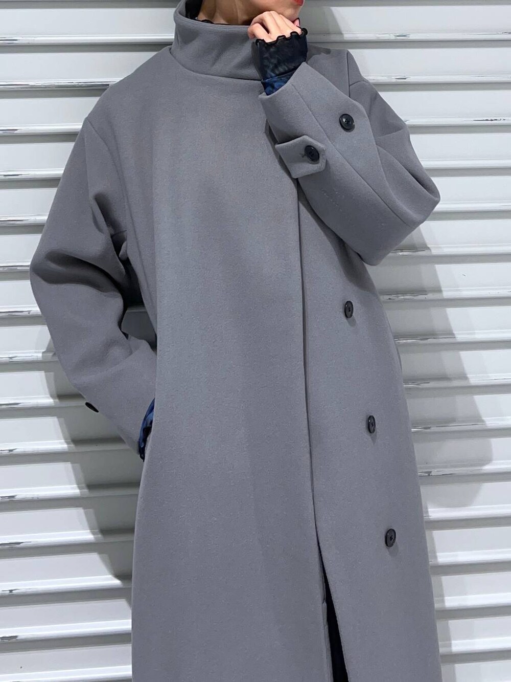 グレー系のチェスターコート、ブラック系のブーツ、ブルー系のスカートを着用したレディースの秋コーディネートの5枚目の写真