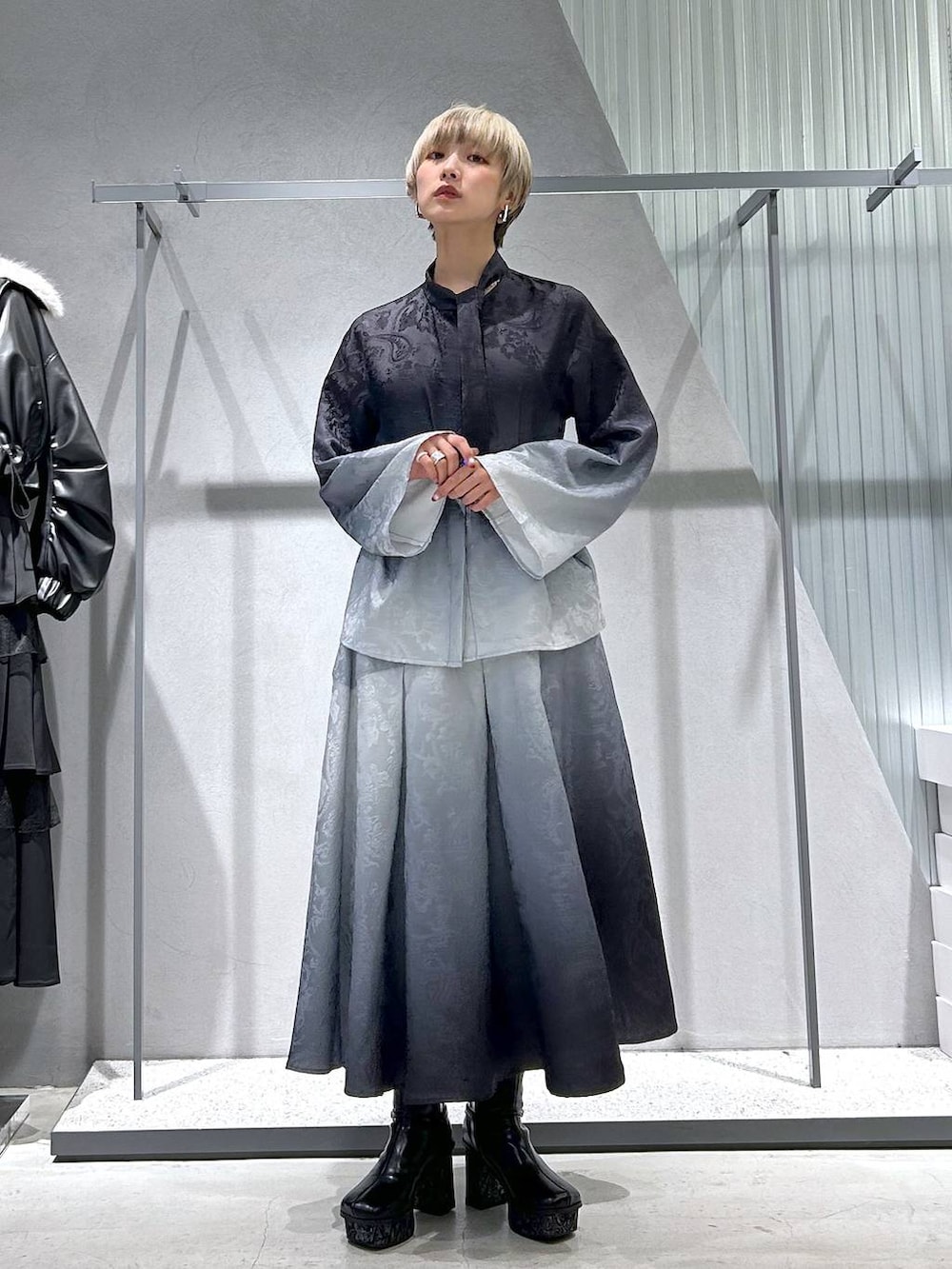 ブラック系のチェスターコート、グレー系のブーツ、ブラック系のシャツ/ブラウスを着用したレディースの冬コーディネートの2枚目の写真