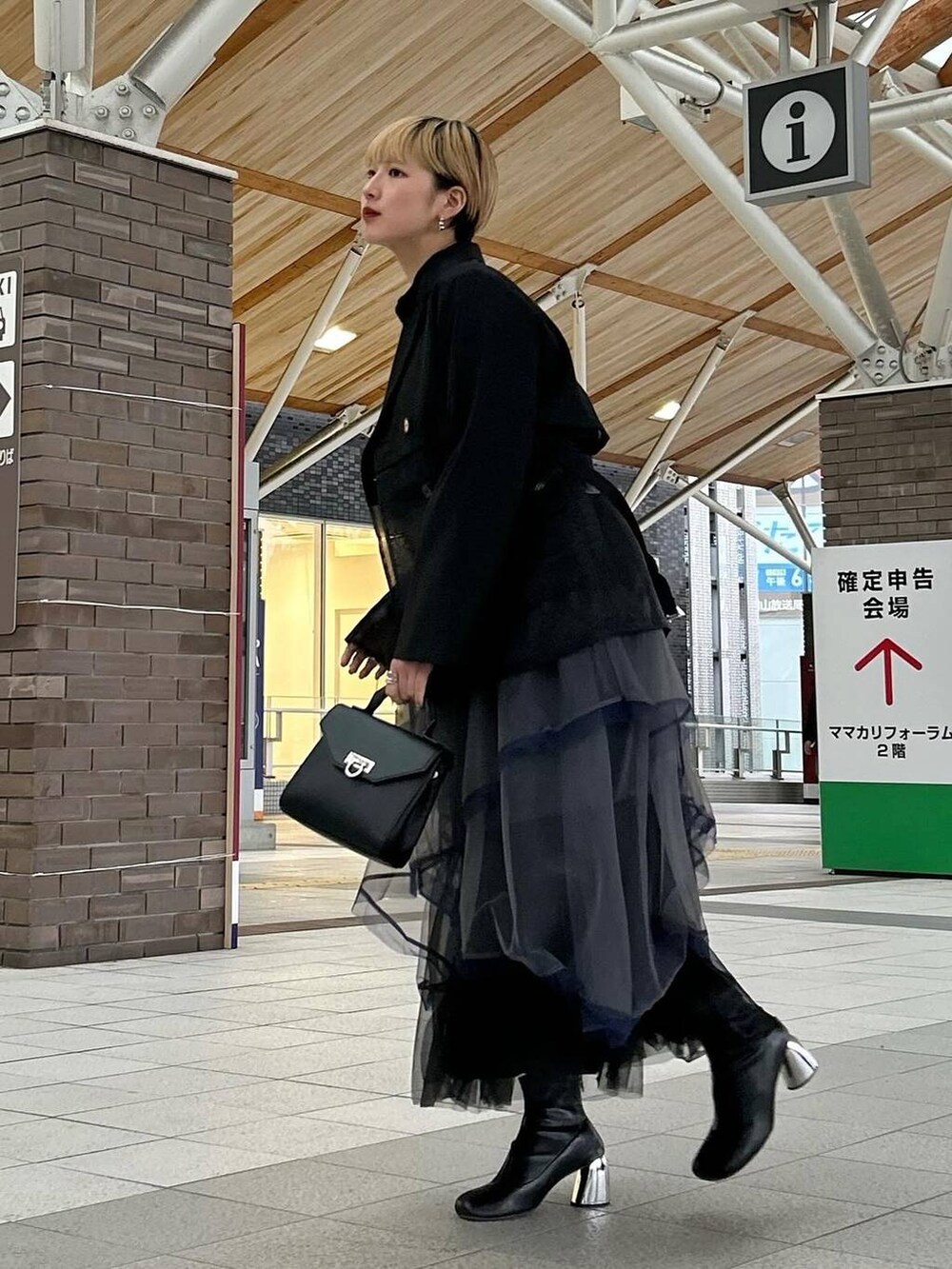 ブラック系のテーラードジャケット、グレー系のスカート、ブラック系のブーツを着用したレディースの春コーディネートの3枚目の写真