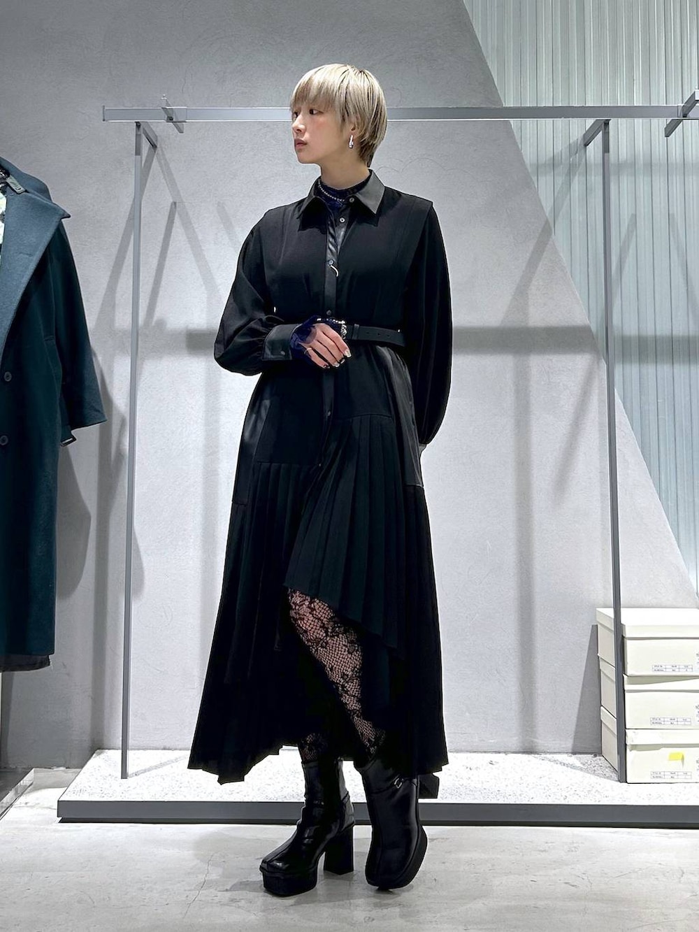 ブラック系のチェスターコート、パープル系のTシャツ/カットソー、グレー系のブーツを着用したレディースの冬コーディネートの2枚目の写真