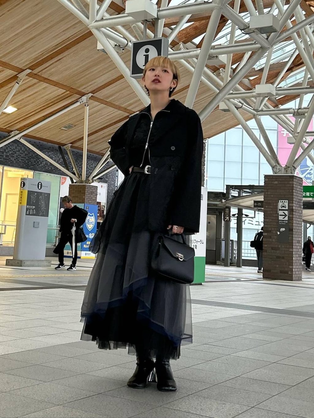 ブラック系のテーラードジャケット、グレー系のスカート、ブラック系のブーツを着用したレディースの春コーディネートの4枚目の写真