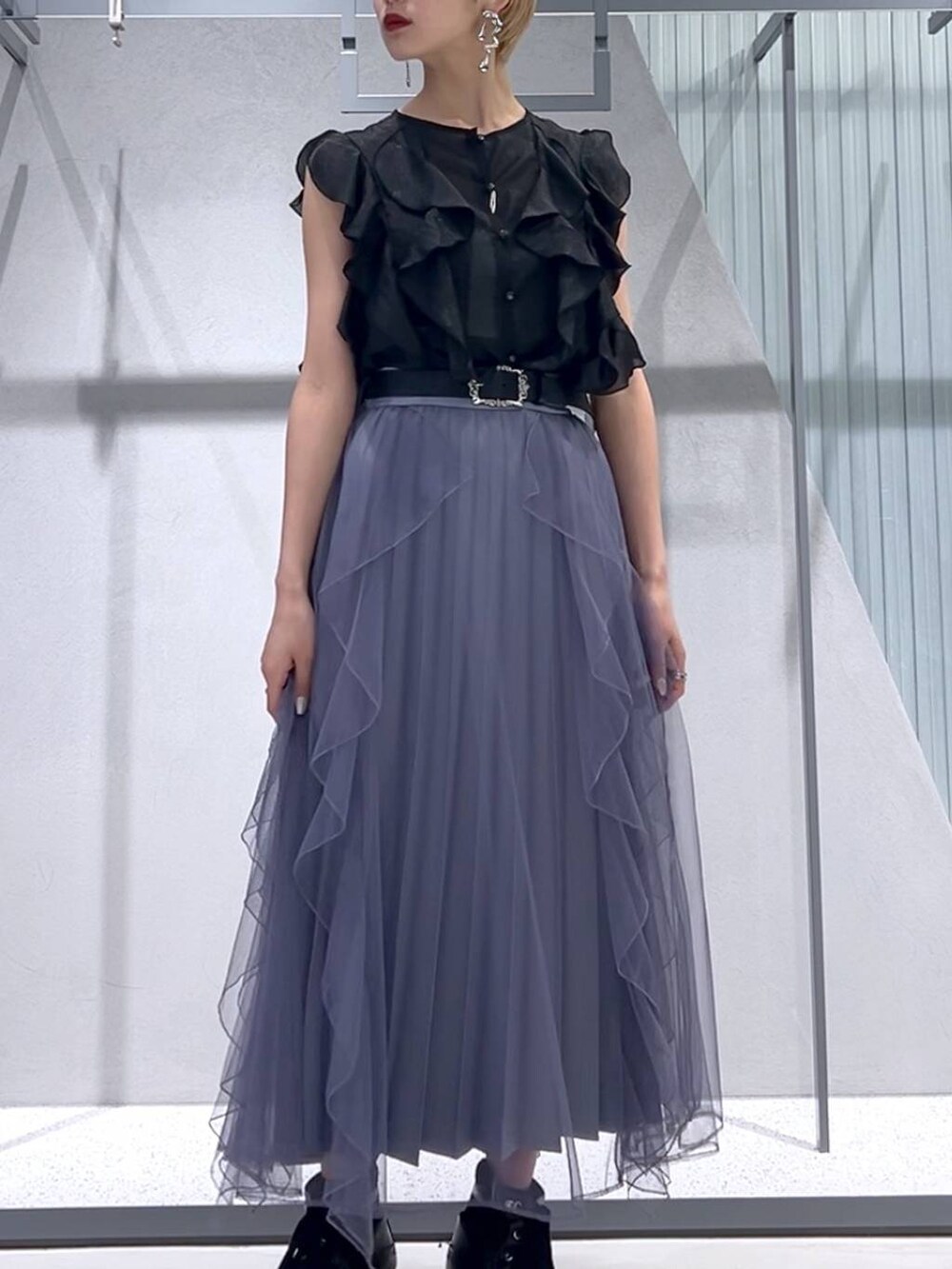 パープル系のスカート、ブラック系のブーツ、ブラック系のシャツ/ブラウスを着用したレディースの春コーディネートの5枚目の写真