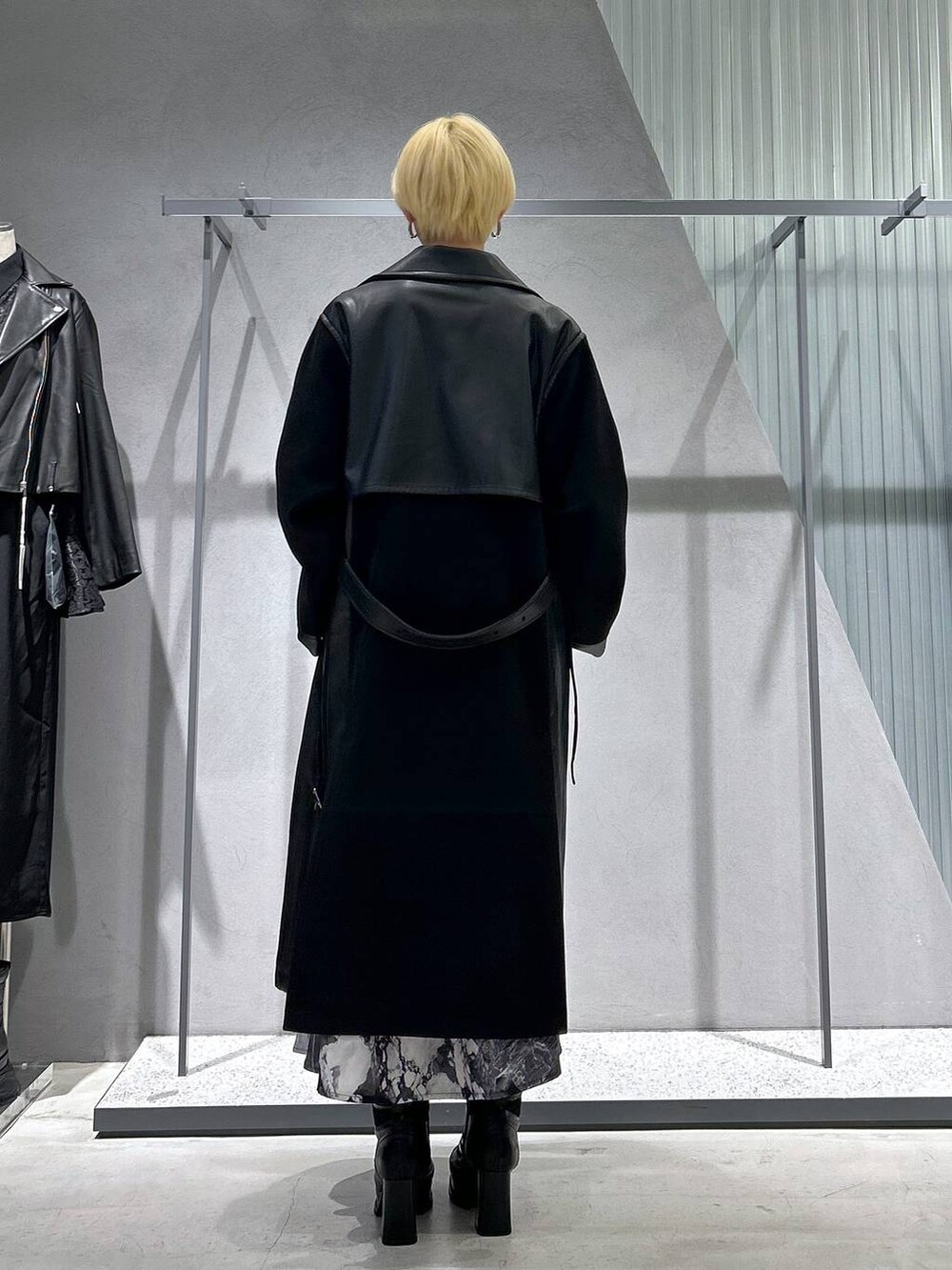 ブラック系のチェスターコート、ブラック系のブーツ、ホワイト系のスカートを着用したレディースの秋コーディネートの6枚目の写真