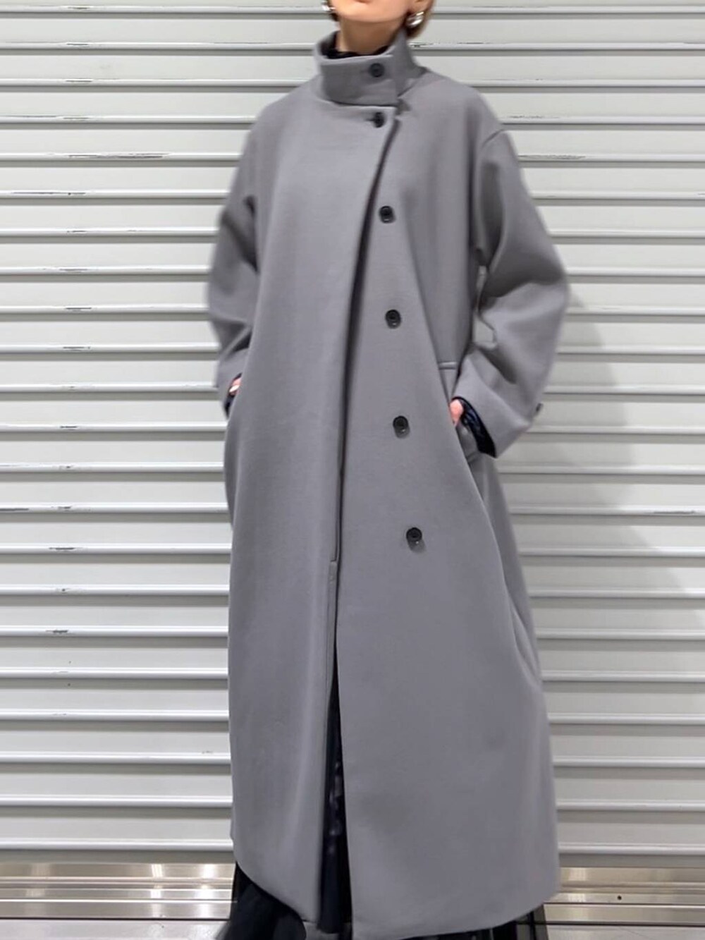 グレー系のチェスターコート、ブラック系のブーツ、ブルー系のスカートを着用したレディースの秋コーディネートの6枚目の写真