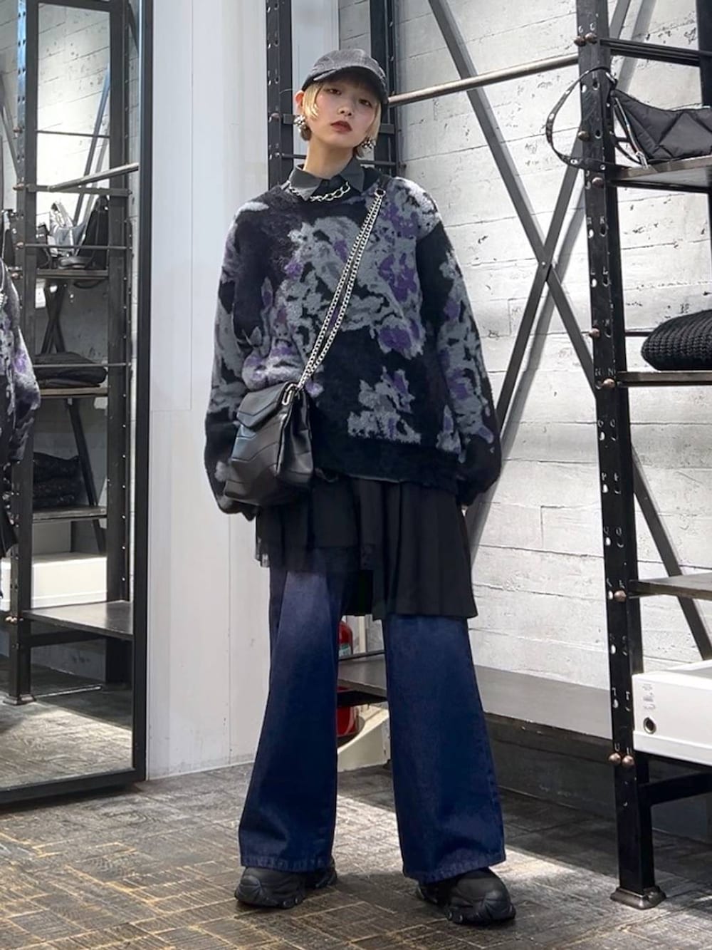 パープル系のデニムパンツ、ブラック系のニット/セーター、ブラック系のブーツを着用したレディースの冬コーディネートの2枚目の写真