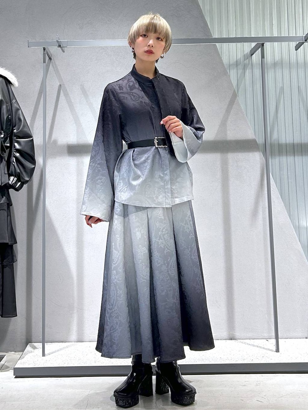 ブラック系のチェスターコート、グレー系のブーツ、ブラック系のシャツ/ブラウスを着用したレディースの冬コーディネートの6枚目の写真