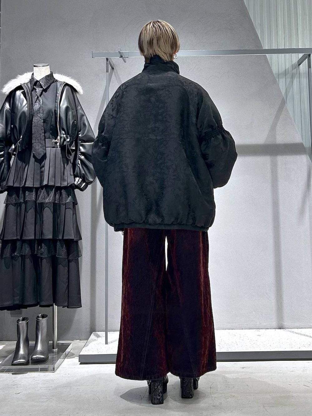 グレー系のブーツ、ブラック系のニット/セーター、レッド系のデニムパンツを着用したレディースの冬コーディネートの4枚目の写真