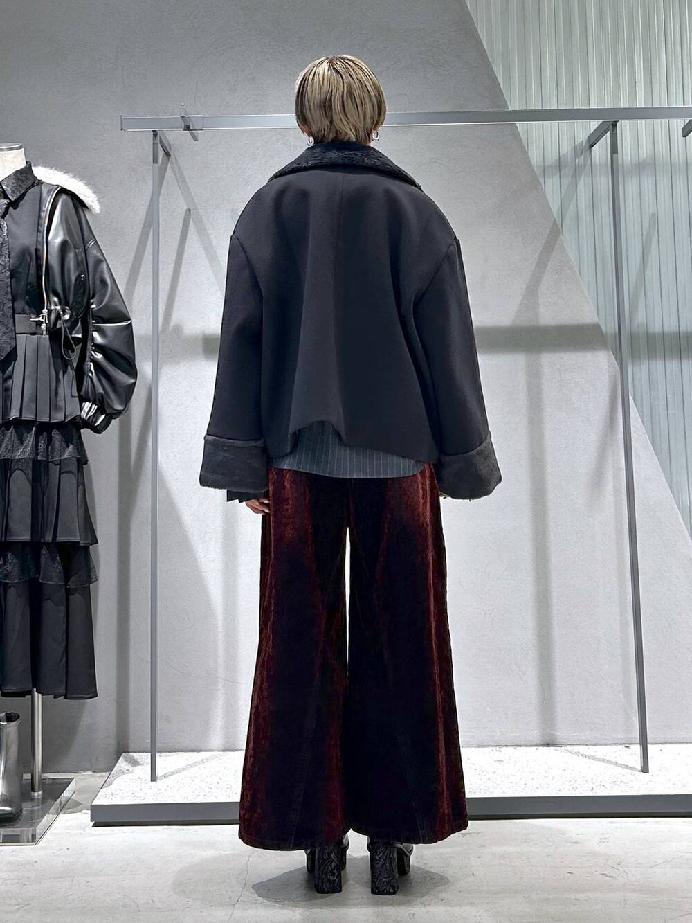 グレー系のチェスターコート、グレー系のブーツ、ブラック系のニット/セーターを着用したレディースの冬コーディネートの4枚目の写真