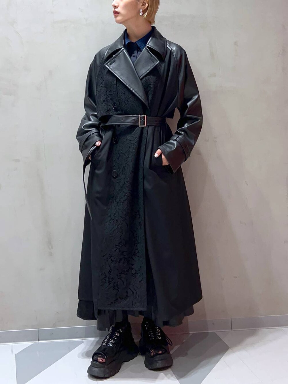 ブラック系のスカート、ブルー系のシャツ/ブラウス、ブラック系のトレンチコートを着用したレディースの秋コーディネートの3枚目の写真